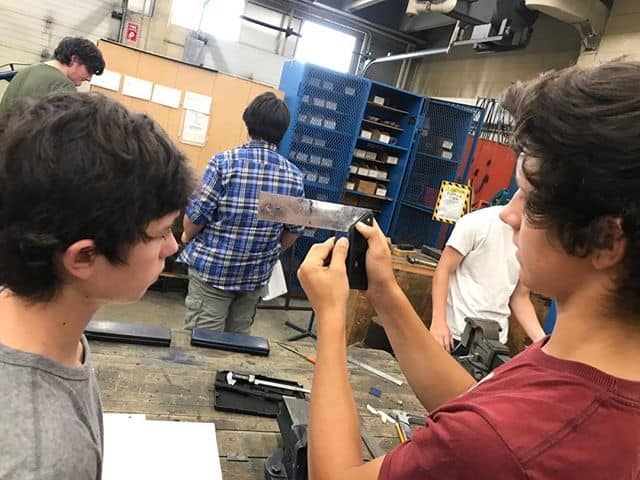 Manufacturing students use hand tools to learn how to make square edges..