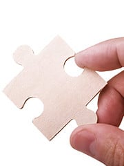 A hand holding a puzzle piece.